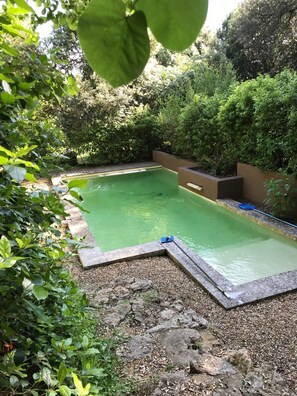 Una piscina al aire libre de temporada, sombrillas