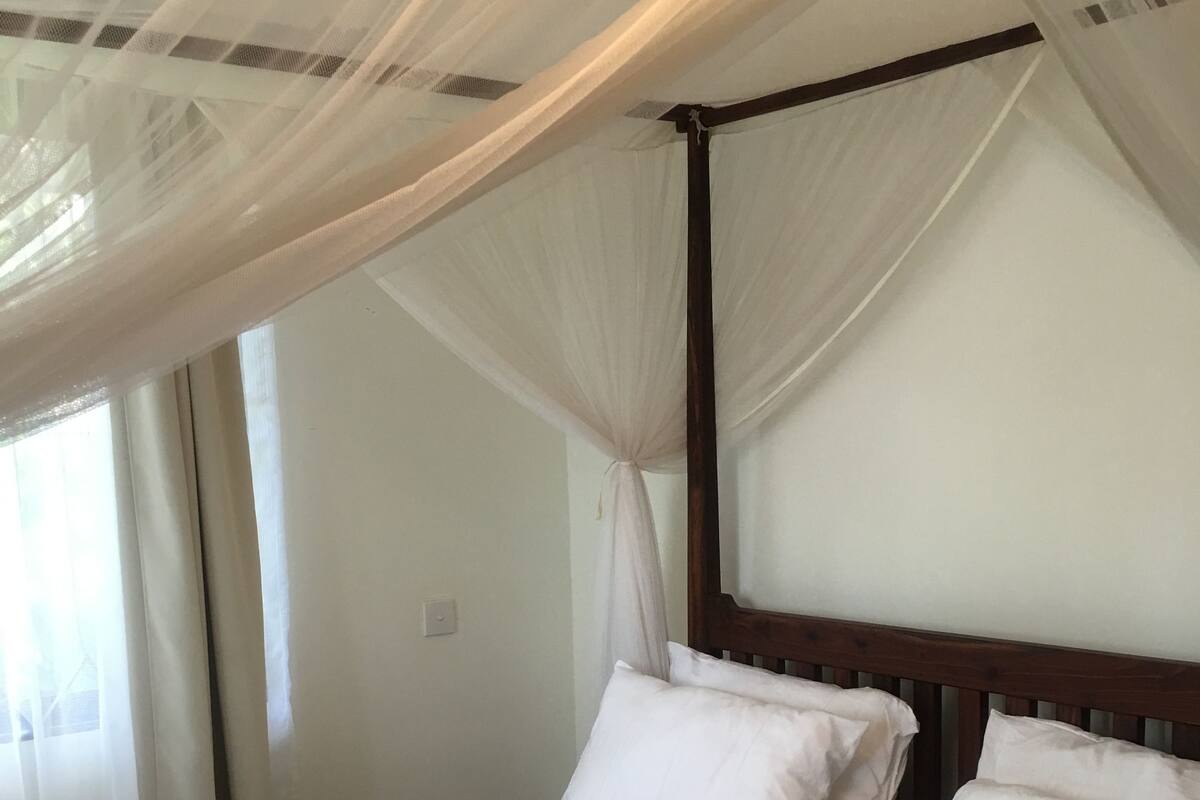 A bed with a canopy, white bedding, and a wooden headboard.