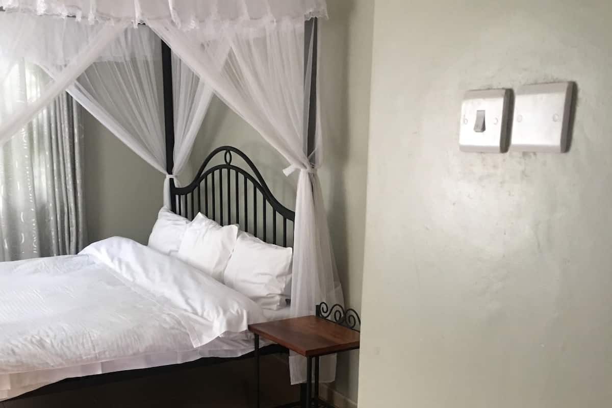 A bedroom with a bed, a bedside table, and a wall-mounted light switch.