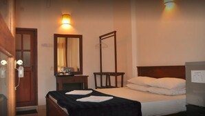 Habitación de hotel con cama, mesita de noche, espejo, armario y televisor de pared.