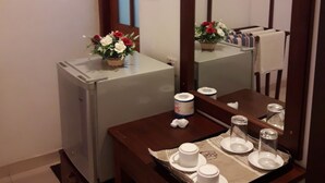 Una habitación pequeña con una mesa dispuesta para el té, un espejo y un refrigerador.
