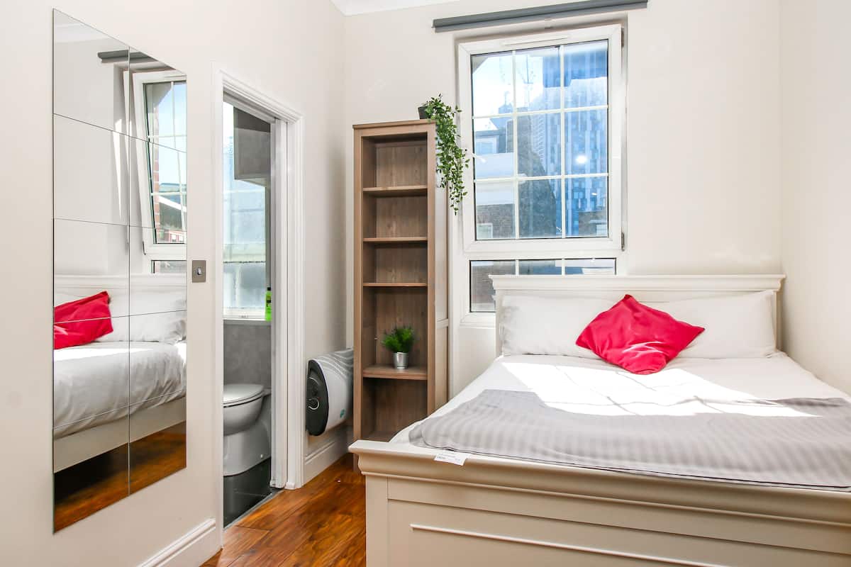 A bedroom with a bed, a window, a mirror, and a closet.