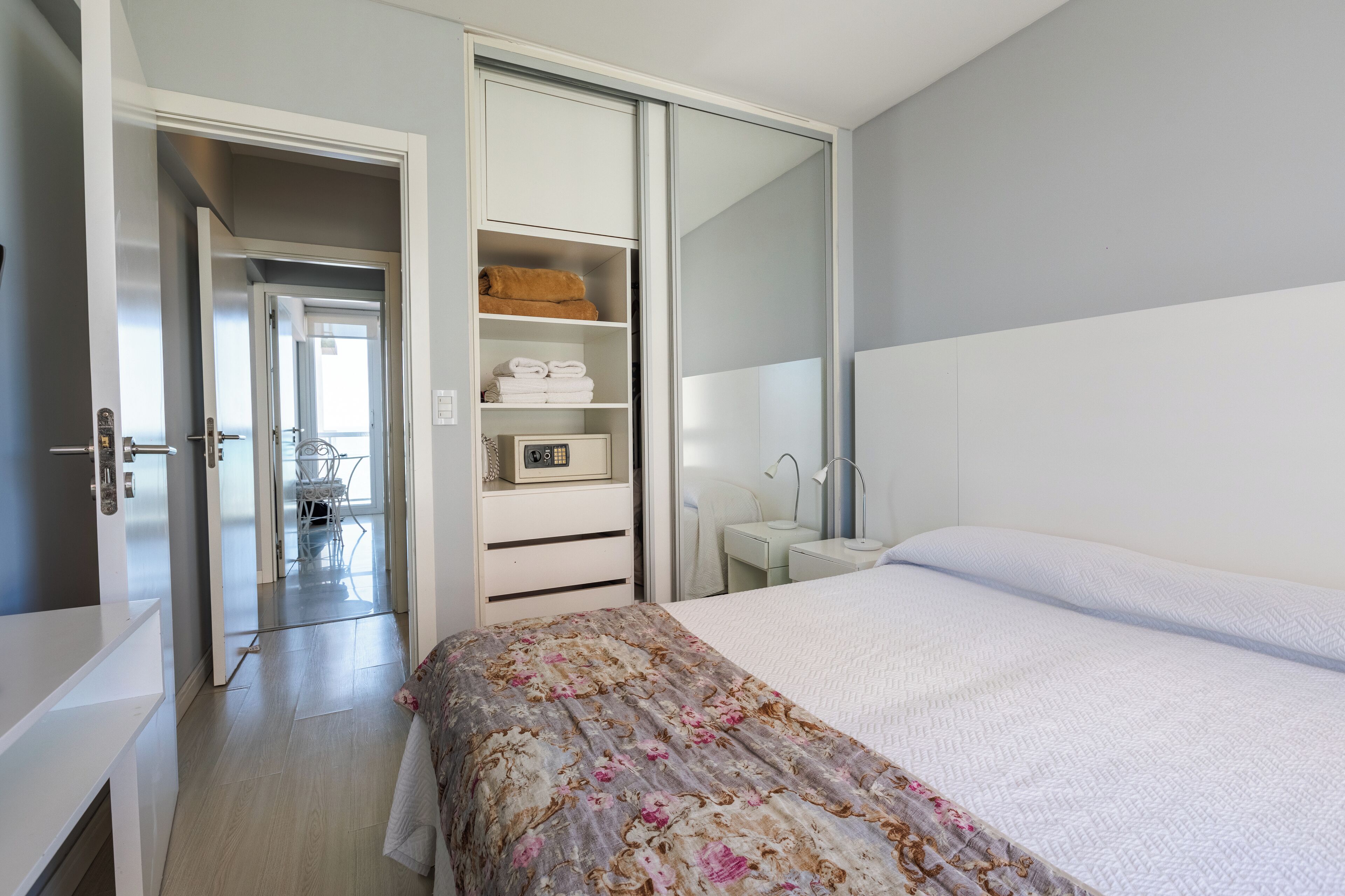 A bedroom with a bed, a wardrobe, a bedside table, and a bathroom visible through an open door.