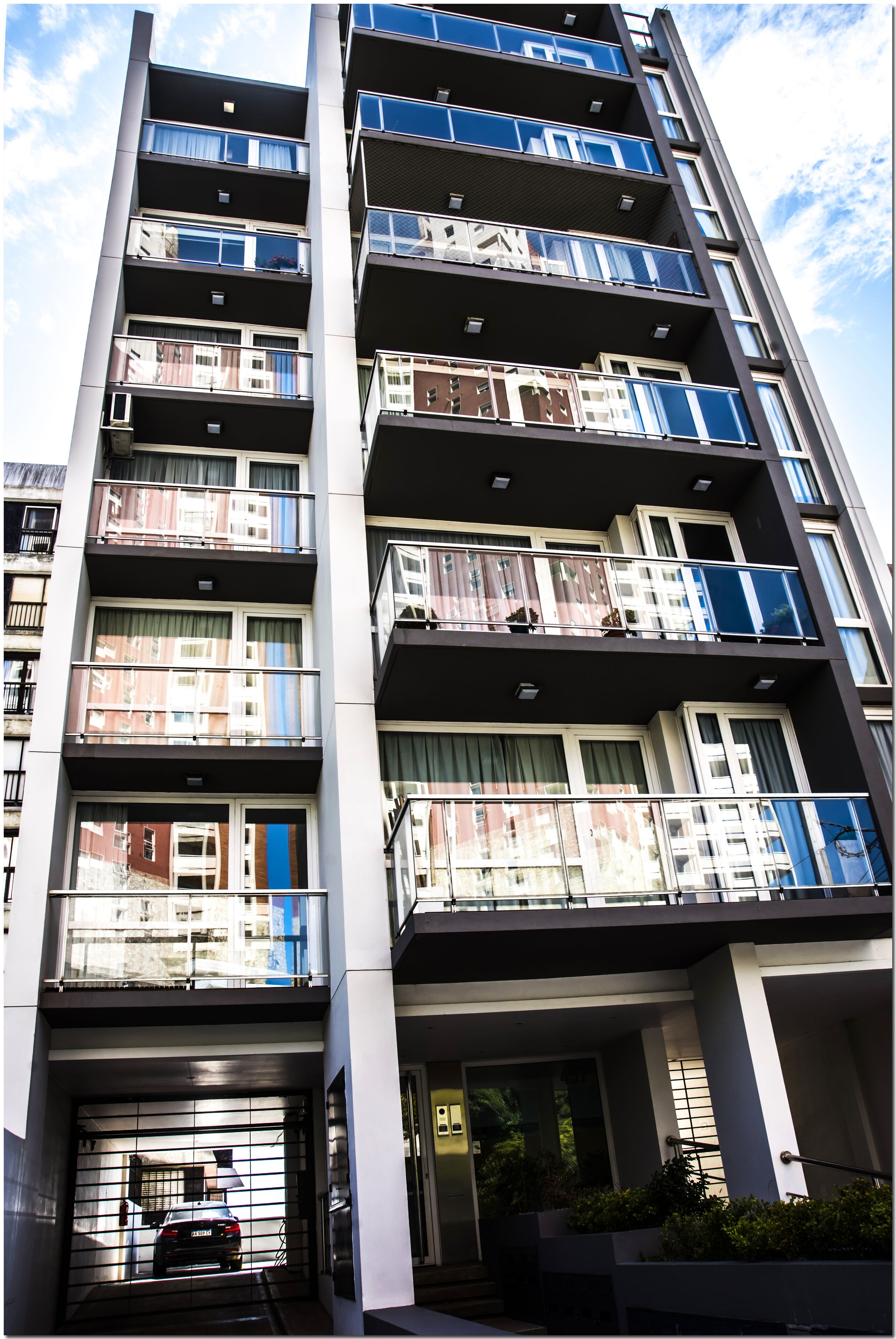 A multi-story residential building with balconies, a garage entrance, and a clear sky.