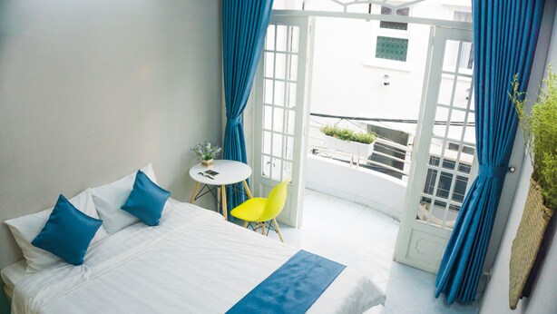 Habitación de hotel con cama, una mesita, una silla y vistas al exterior.