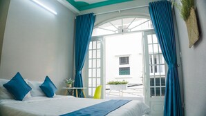Habitación de hotel con cama, cortinas azules, una ventana y vista al exterior.