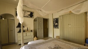 Un dormitorio con cama, armario, cómoda y puerta que da a otra habitación.