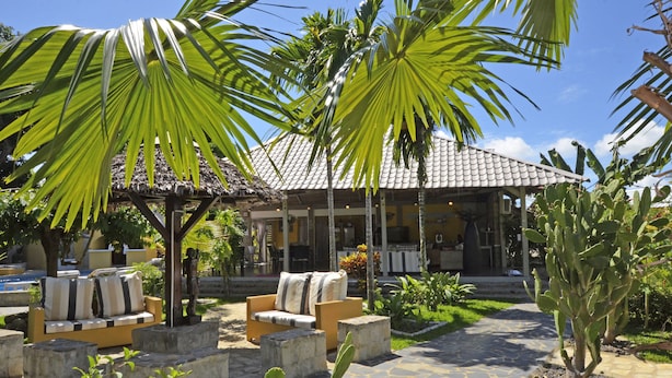 A courtyard with outdoor seating, a thatched-roof structure, and a cactus plant. - Le Laugaut's Bungalows (Nosy Be)