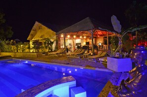 A pool area with lounge chairs and a covered seating area at night. - Le Laugaut's Bungalows (Nosy Be)