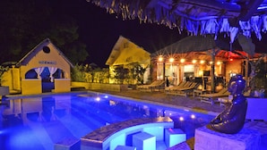 A nighttime swimming pool area with a statue, lounge chairs, and a building labeled "SALLE DE MESSAGERIE". - Le Laugaut's Bungalows (Nosy Be)