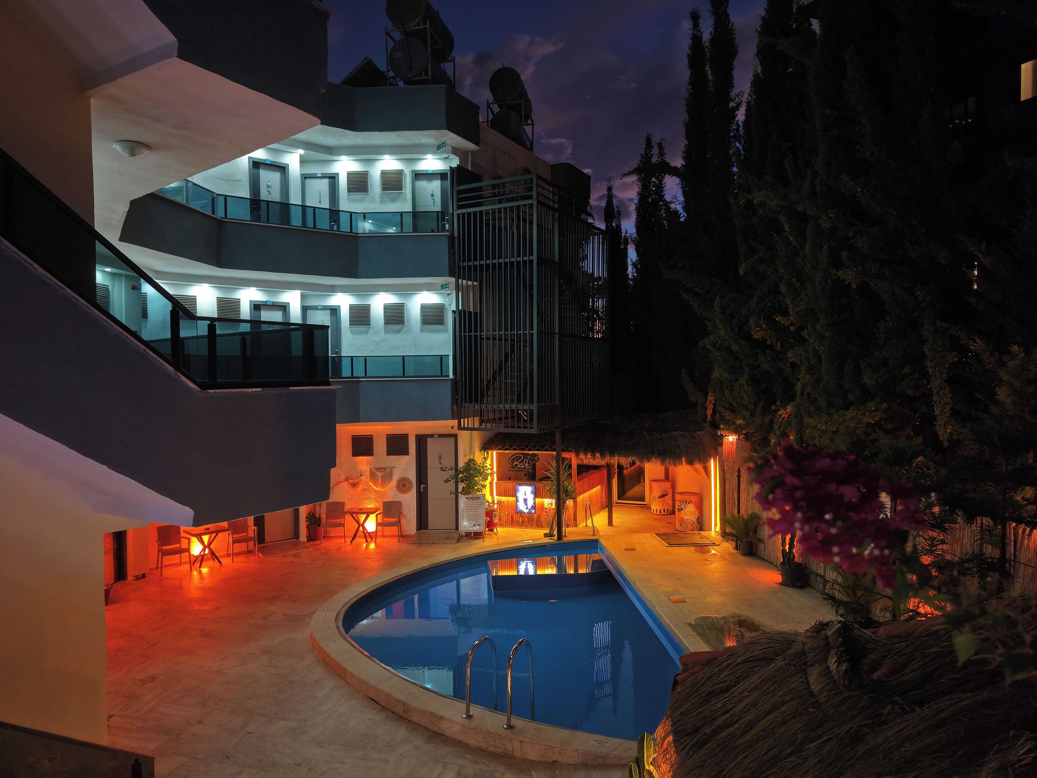 A modern building with a swimming pool, outdoor seating, and a staircase.
