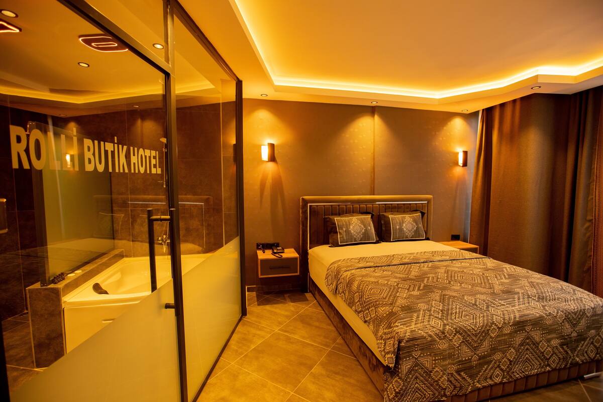 A hotel room with a large bed, a glass-enclosed shower, and a visible sign reading "ROLLI BUTIK HOTEL".