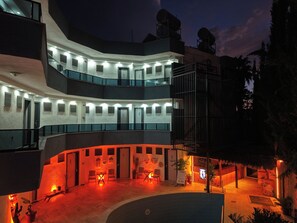 Un hôtel à plusieurs étages doté de balcons, d’un espace piscine et de coins salon extérieurs.