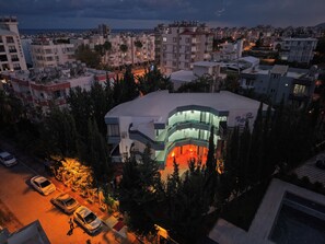 A modern building with a curved facade and multiple balconies, surrounded by trees and other residential buildings. -  Rolli Butik Hotel (Anamur)