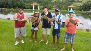Un grupo de personas de pie junto a un lago sosteniendo peces.