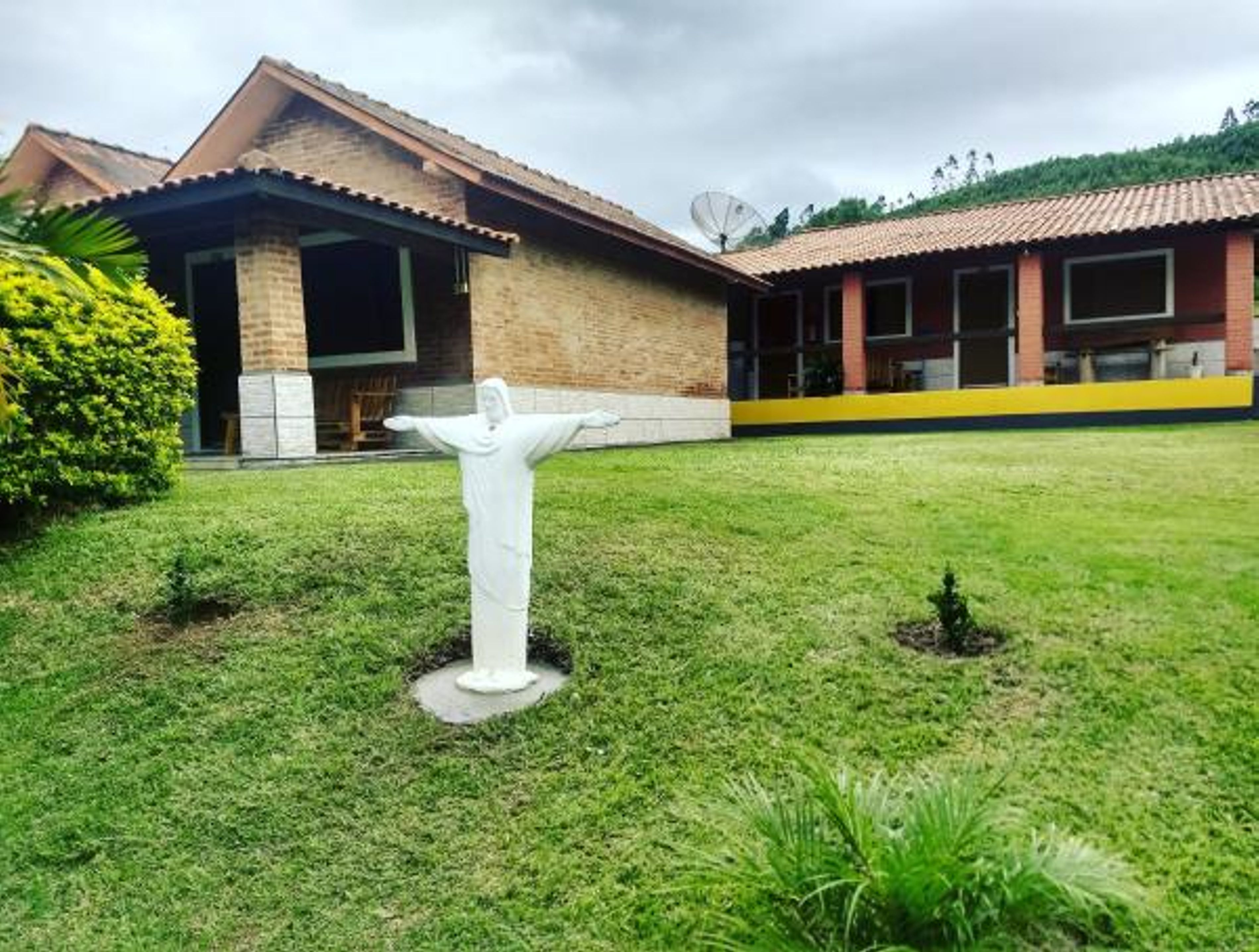 A building with a brick facade and a tiled roof, a grassy lawn, and a white statue in the foreground.