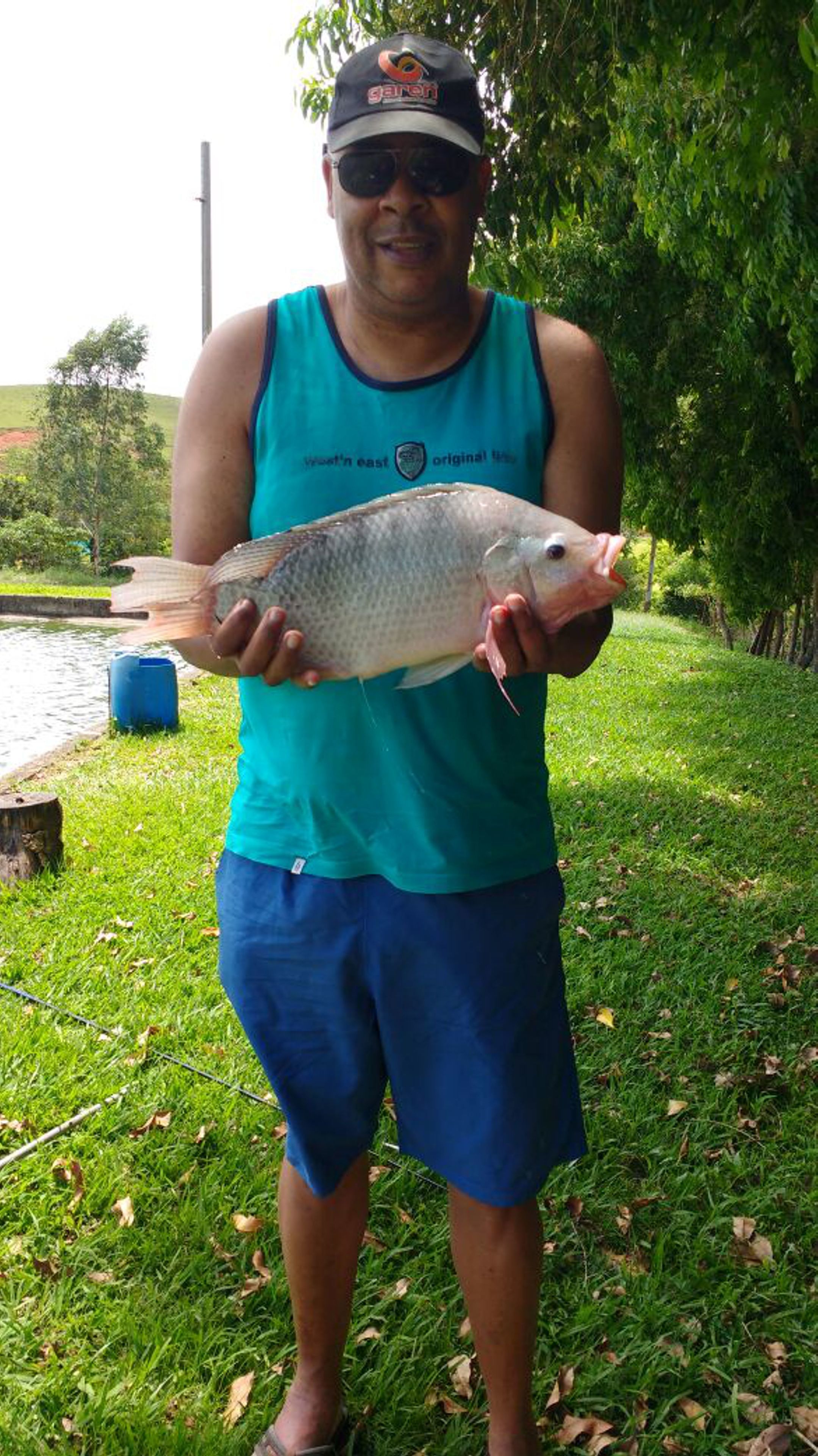 A person holding a fish outdoors.
