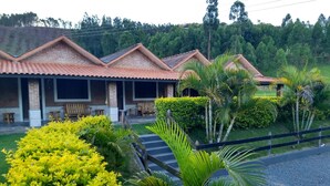 A row of brick buildings with tiled roofs, outdoor seating, and lush greenery. - Pousada e Pesca Esportiva Fazolin (Socorro)