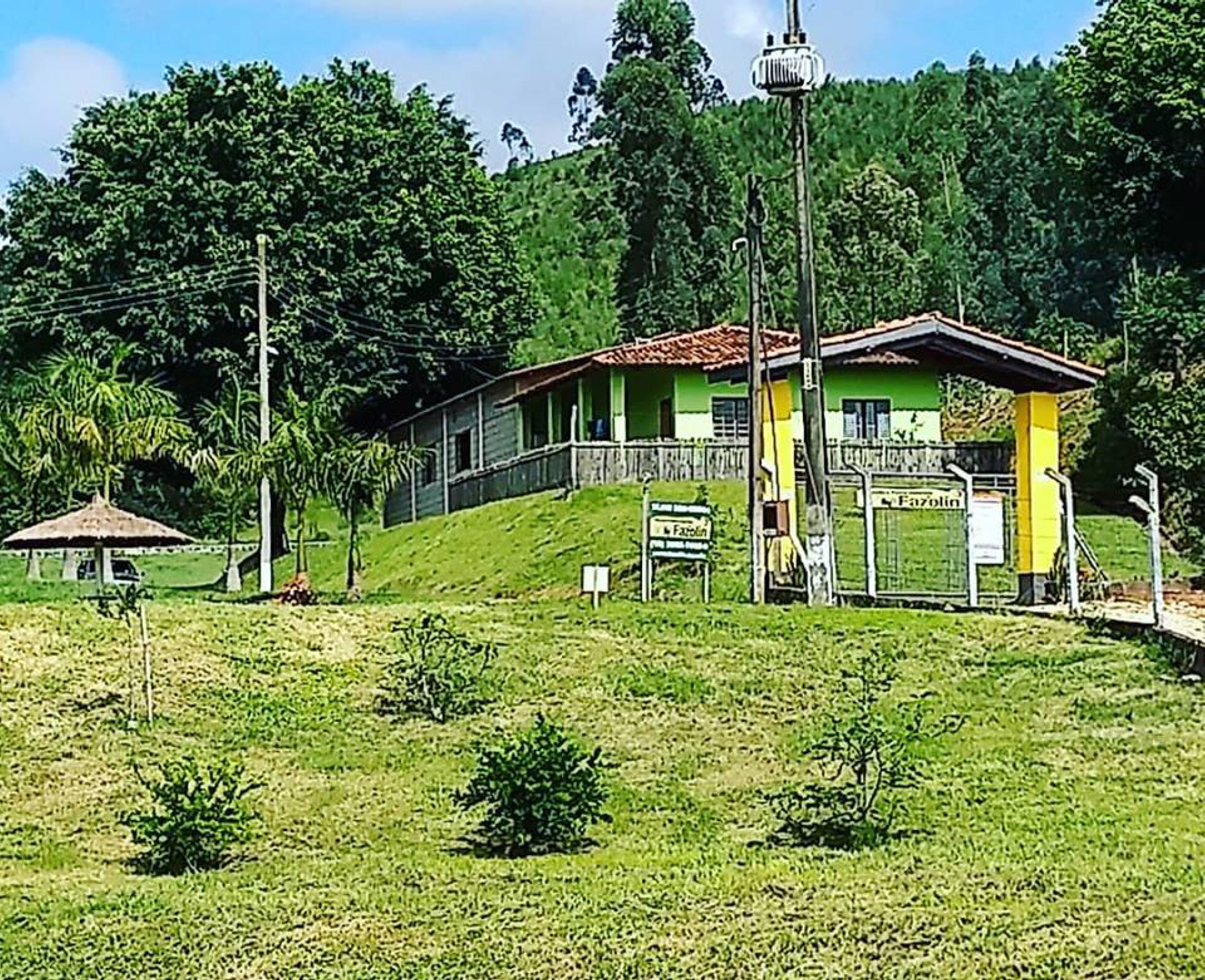 Um edifício de dois andares com fachada verde e amarela, uma varanda e uma pequena construção anexa.