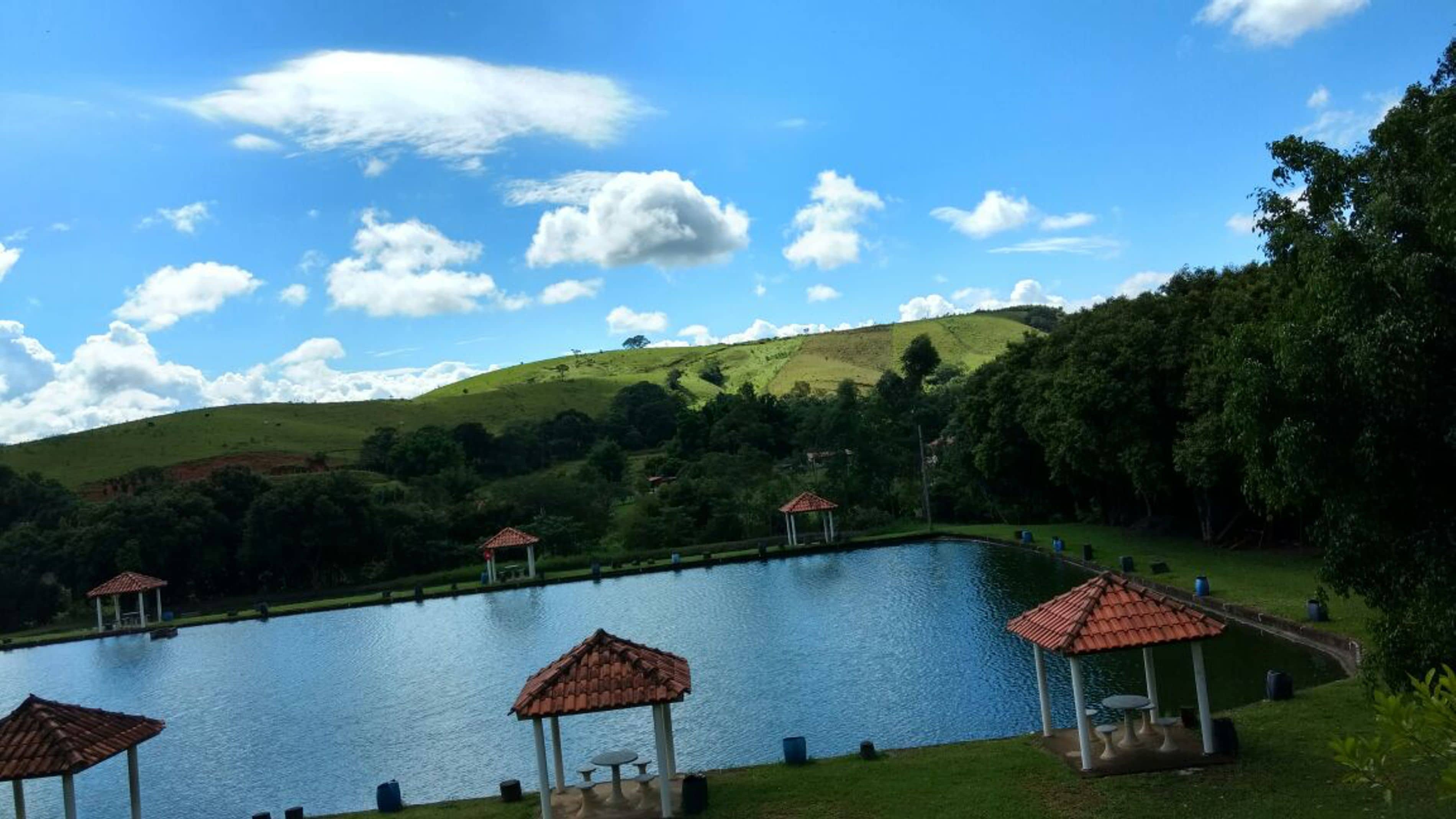 Un área de piscina exterior tranquila, con varios quioscos y una vista despejada de un paisaje montañoso.