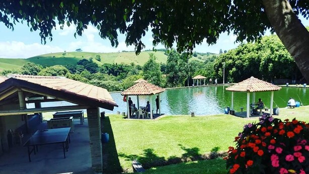 A lakeside outdoor area with a gazebo, a covered seating area, and a flower bed. - Pousada e Pesca Esportiva Fazolin (Socorro)