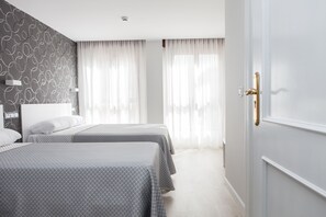 Ett hotellrum med två sängar, en vägg med ett mönster och en dörr med ett guldhandtag.