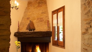 A cozy room with a stone fireplace, wicker furniture, and a tiled floor. - Can Barrull (Palau-Sator)