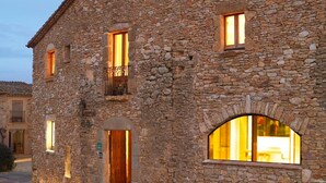 A stone building with a wooden door and multiple windows, including an arched window. - Can Barrull (Palau-Sator)