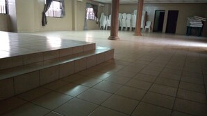Ein geräumiger Saal mit Fliesenboden, einer Treppe und mehreren Säulen.