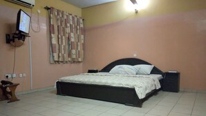 Ein Schlafzimmer mit Bett, Nachttisch, Wand-Fernseher und Deckenventilator.