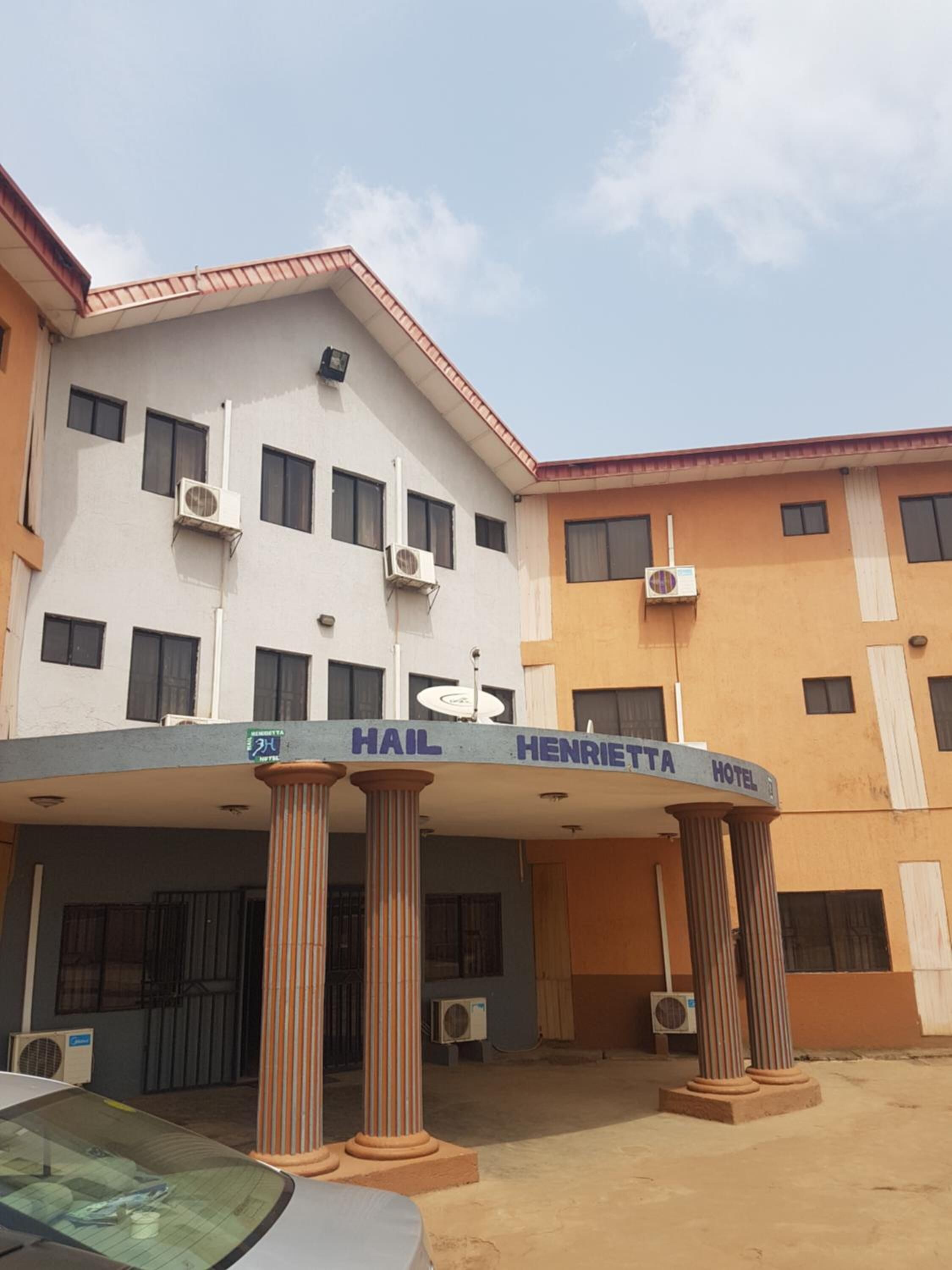 A hotel with a covered entrance, columns, and air conditioning units.