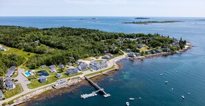 An aerial view of a coastal residential area with houses, a dock, and boats.