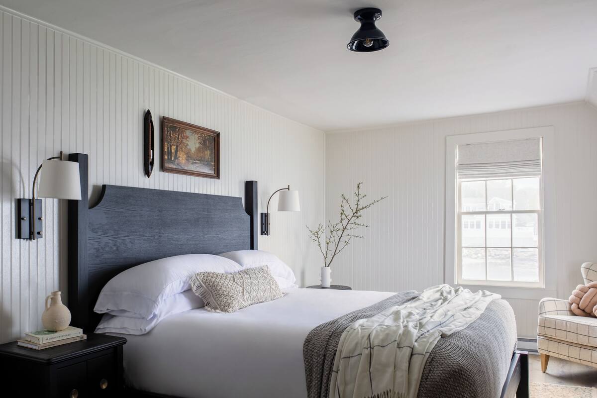 Ein Schlafzimmer mit Bett, Nachttischen, Fenster und einer Wandlampe.