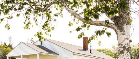 A white single-story house with a front porch, a chimney, and a well-maintained lawn.