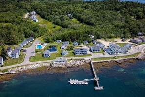 An aerial view of a coastal residential area with houses, a dock, and a pier.