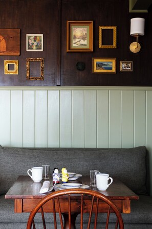 A wooden table with a chair, a bench, and a wall with framed pictures.