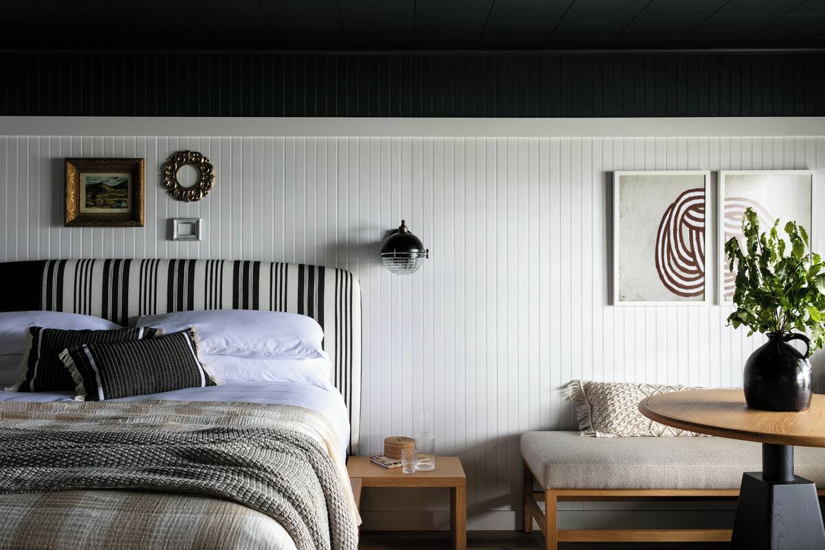 Ein Schlafzimmer mit einem Bett, einem Nachttisch und einem runden Tisch mit einer Pflanze.