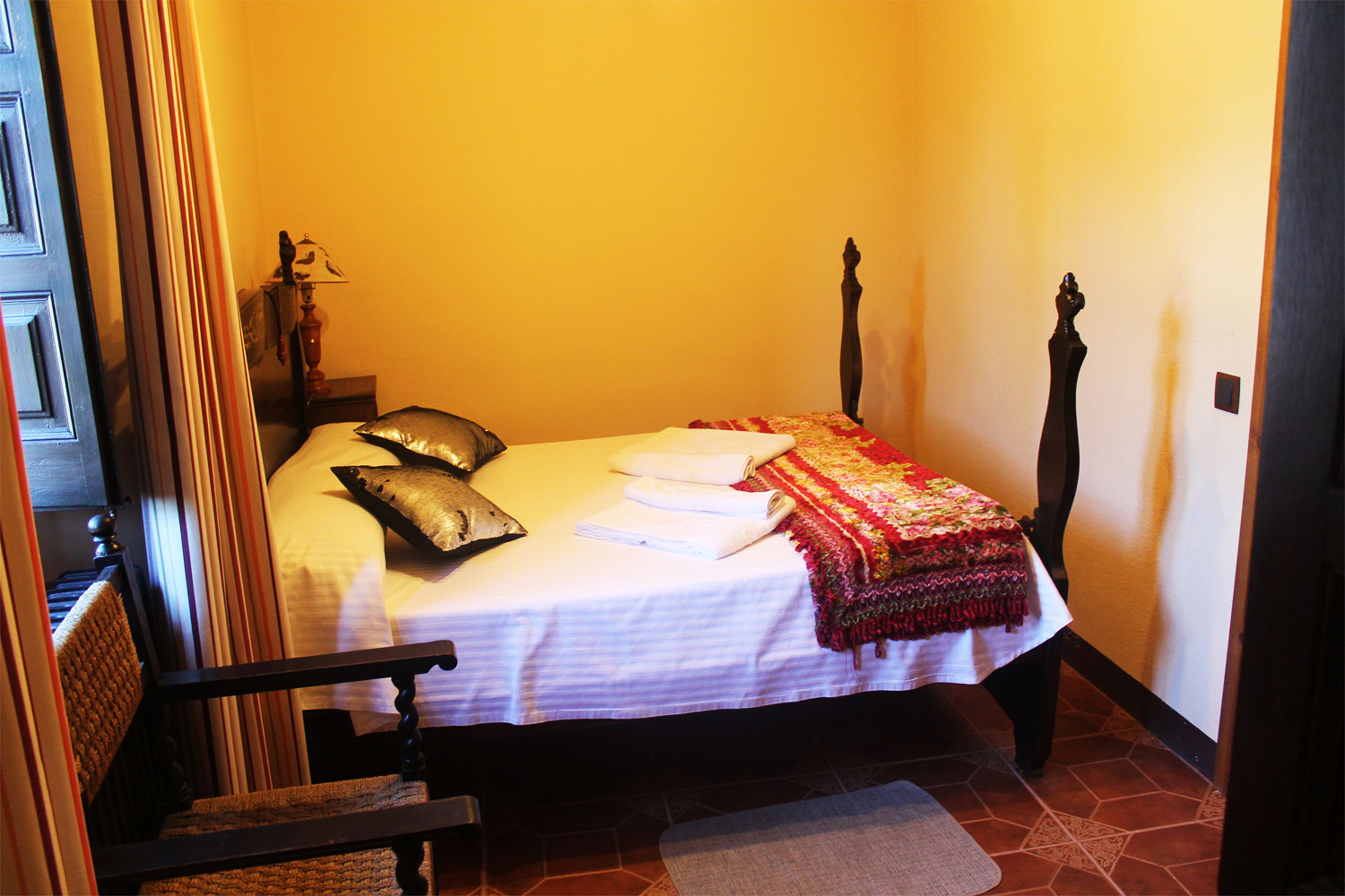 A bedroom with a bed, pillows, a bedside table, and a lamp.