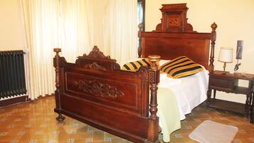 A traditional wooden bed with a headboard, a bedside table with a lamp, and a patterned floor.