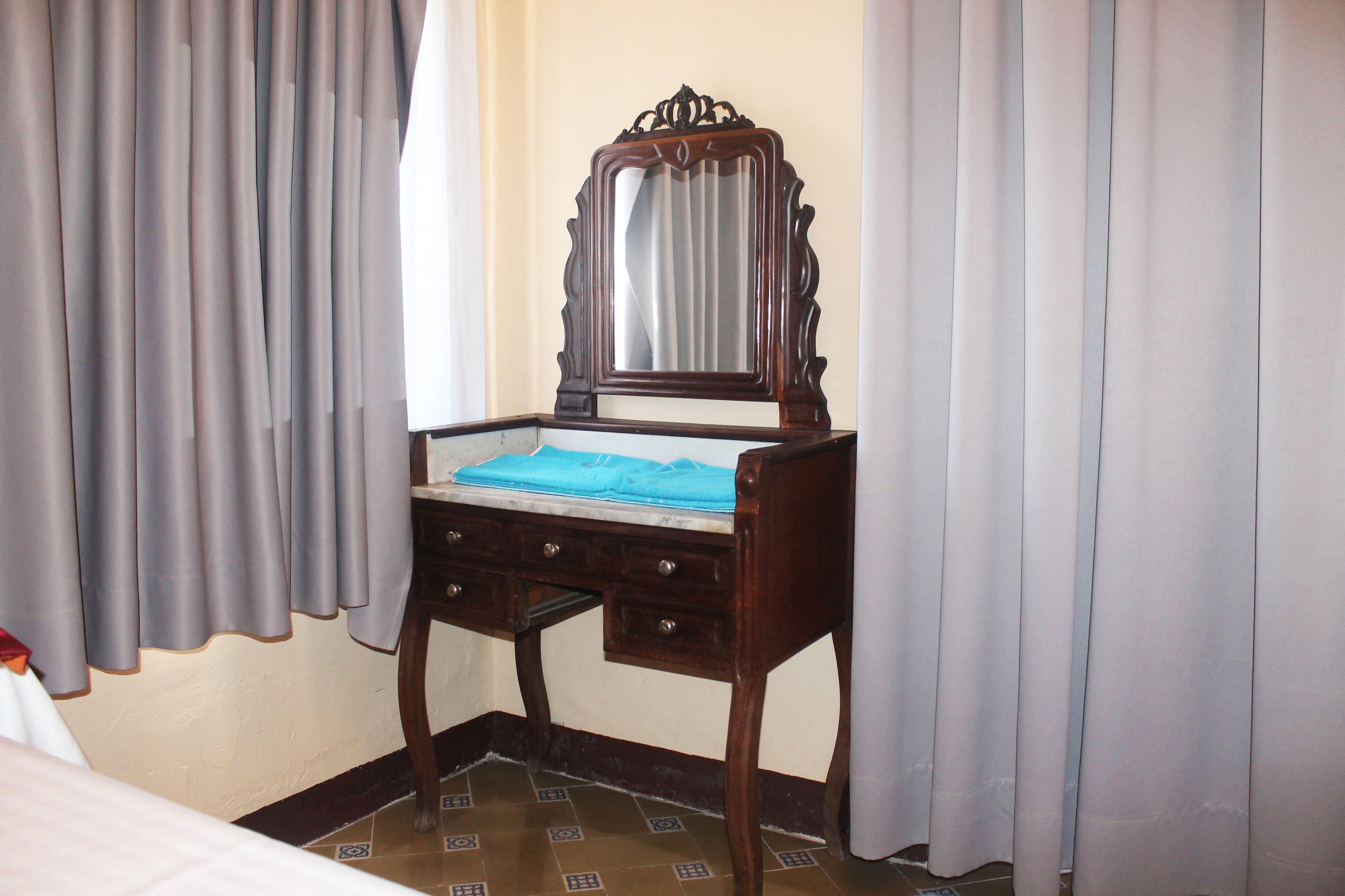 A wooden desk with a mirror, a blue cloth, and a drawer.