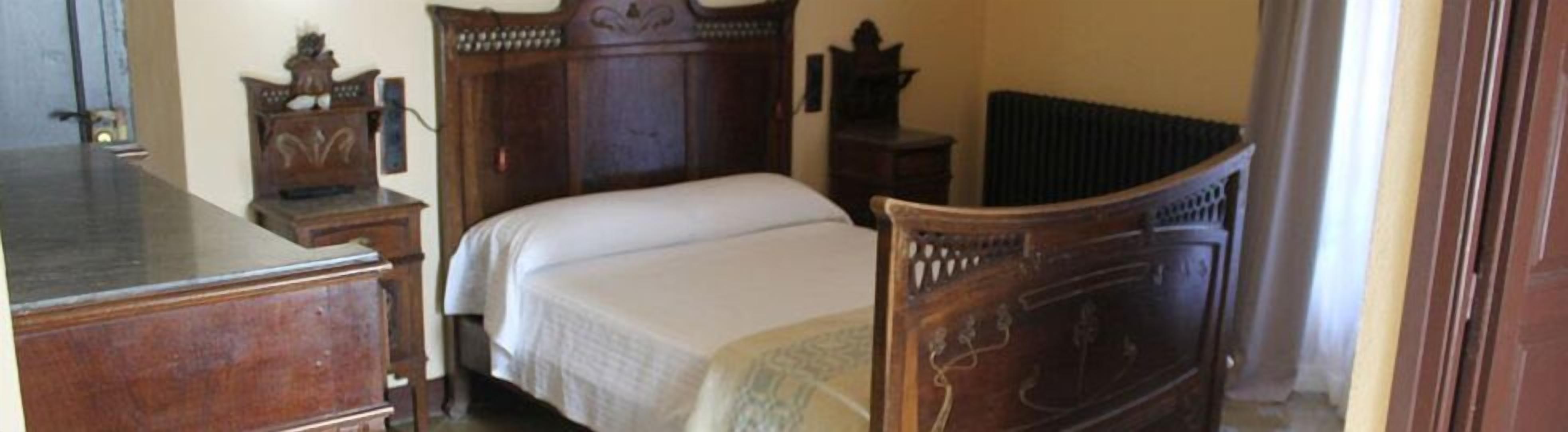 Quarto com cama de madeira, cómoda e radiador.
