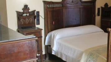 Quarto com cama de madeira, cómoda e radiador.