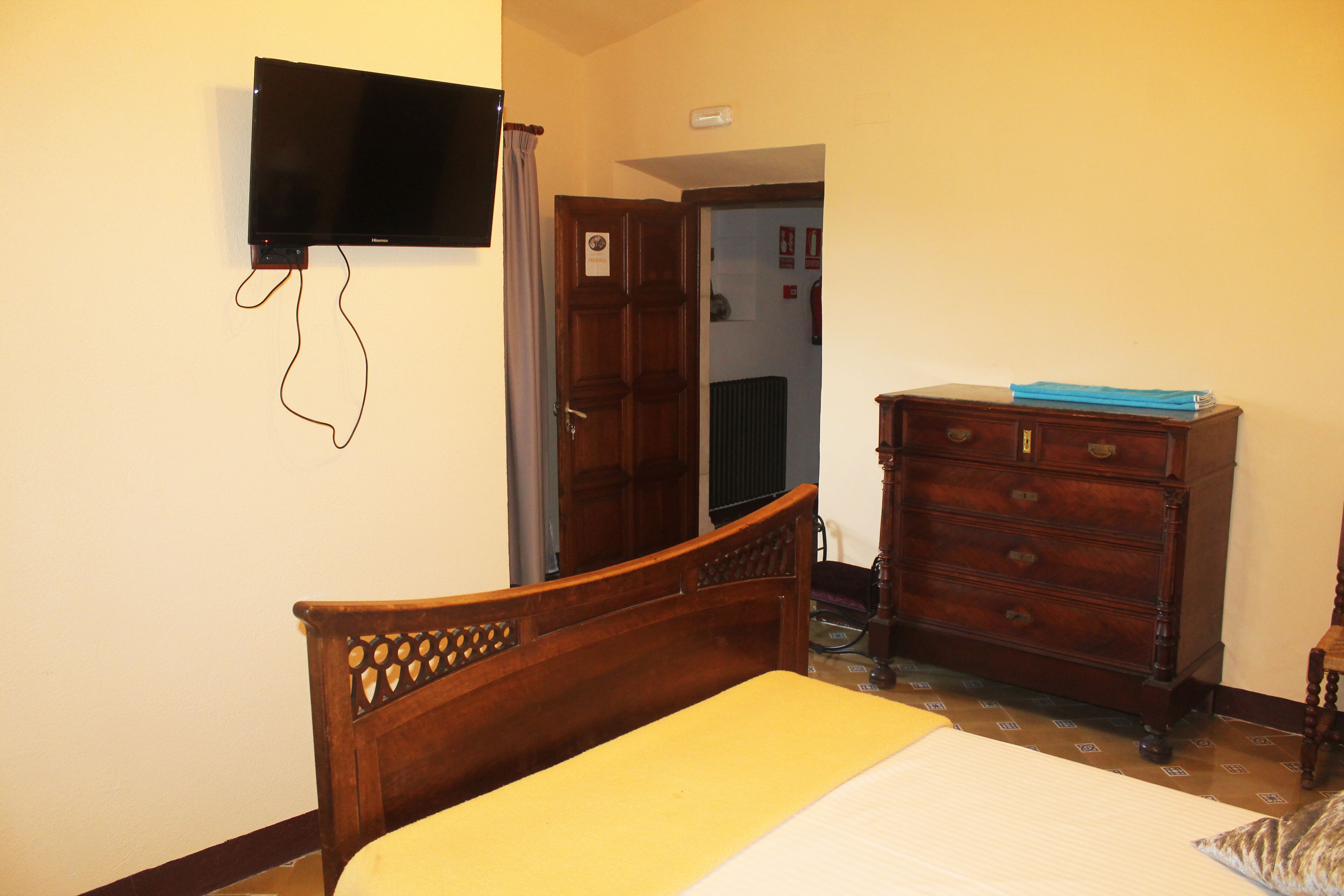 Un dormitorio con una cama de madera, un aparador y un televisor de pantalla plana montado en la pared.