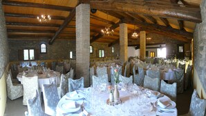 A large banquet hall with multiple round tables set for a formal event, featuring white tablecloths and floral chair covers. - Hostal Rural Mas Blanc (Sant Marti de Centelles)