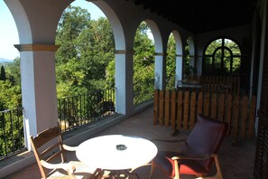 A covered outdoor seating area with a round table and chairs, surrounded by white columns and a wooden fence. - Hostal Rural Mas Blanc (Sant Marti de Centelles)