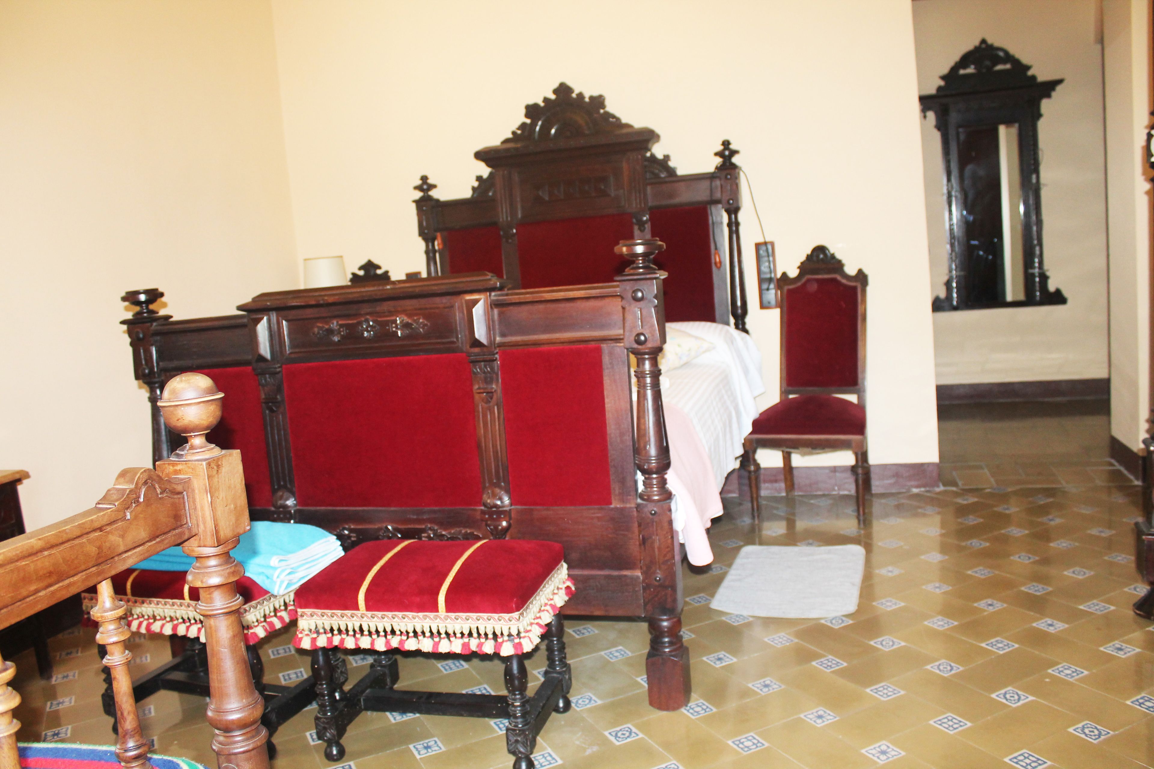 Une chambre à coucher de style traditionnel, avec un lit à baldaquin, une chaise en bois et un petit banc.