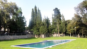 A rectangular swimming pool surrounded by a stone wall and lush green grass. - Hostal Rural Mas Blanc (Sant Marti de Centelles)