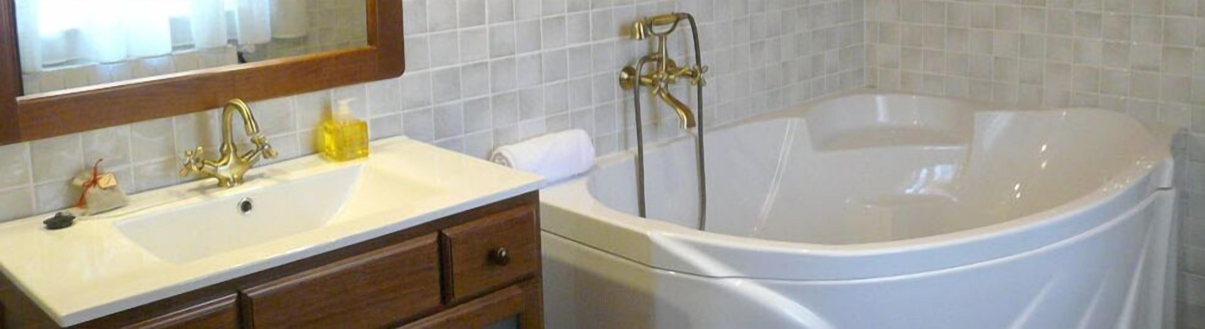 Un baño con bañera, lavamanos, espejo y toallero.