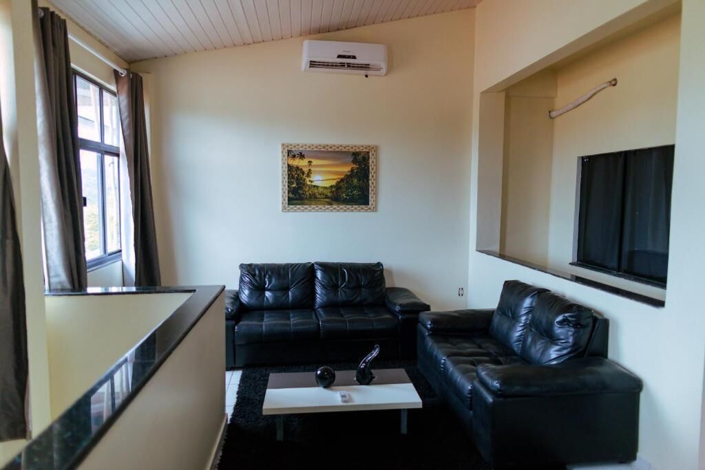 A living room with a black leather sofa, a coffee table, and a framed picture on the wall.