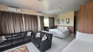 A hotel room with a black leather sofa, a bed, a desk with a computer, and a window with curtains. - Carajas Hotel (Parauapebas)